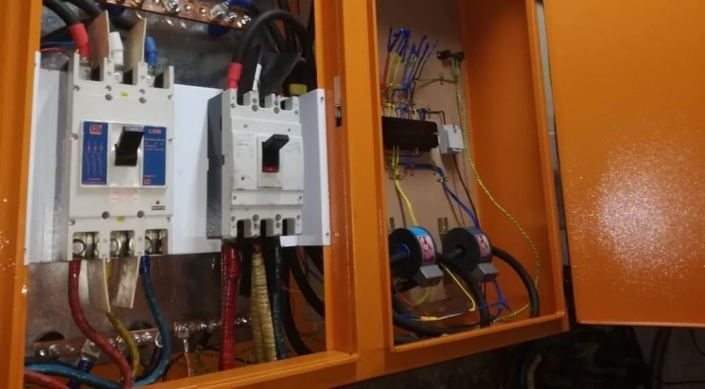 Open orange distribution board with circuit breakers, cabling and a current transformer