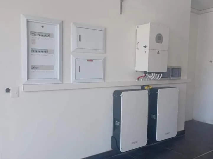 Wall-mounted inverter, distribution boards and two battery cabinets on a white wall