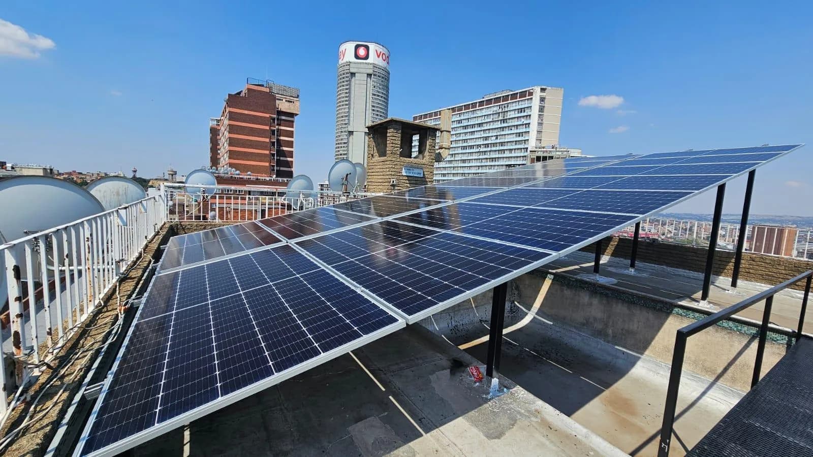 Rooftop solar panel array on a Johannesburg building with the city skyline behind it