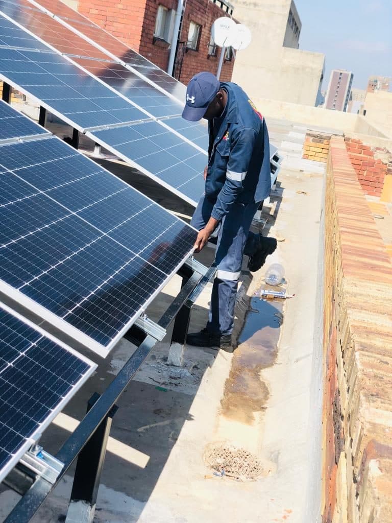 Technician installing solar panels on a concrete roof